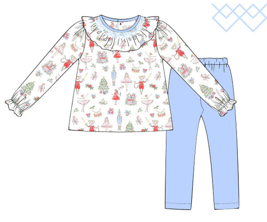 Children's outfit with nutcracker patterned top and blue pants on a white background