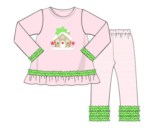 Children's pajama set with pink top and pants featuring a gingerbread house design on a white background.